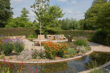 Sommerlicher Park oder Landschaftsgarten mit Rondell, Brunnen, Wasserspielen und teichartigem Graben