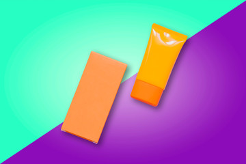 Orange sunscreen spf cream on violet and turquoise background. Fashion accessory. Summer outfit. Vacation and travel item. Advertising commercial concept flat lay