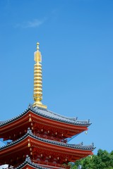 Fototapeta na wymiar Vivid red pagoda in Fukuoka, Japan. Glowing golden spire and green trees