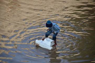 インドの首都のデリー　スラムの浸水した道路で遊ぶ少年