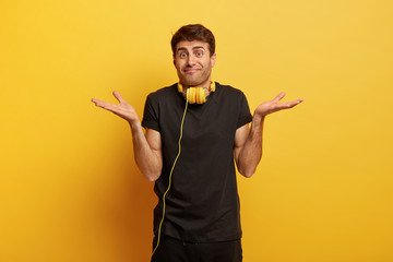 Unbothered indifferent man spreads hands sideways, has no idea, stands uncertain and doubtful,...