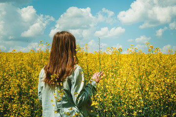 girl in Rapeseed field, Blooming Rapeseed Against the blue sky with clouds