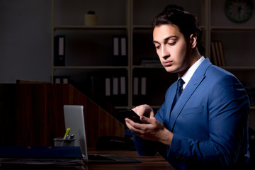 Young male employee working night in the office