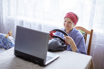 Senior woman enjoying car racing video game on laptop at home