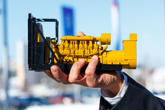 A toy model of a gas generator set is in the male hand.