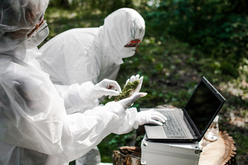 Ecological problem. Pollution. Examine soil. Scientist in protective mask and suit taking water...