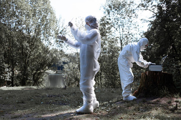 Ecological problem. Pollution. Examine soil. Scientist in protective mask and suit taking water...
