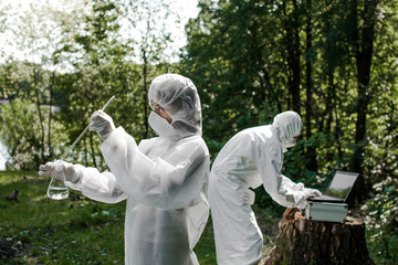 Ecological problem. Pollution. Examine soil. Scientist in protective mask and suit taking water...