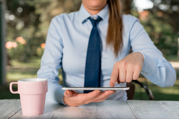 Business concept with female business person sitting by the table and holding mobile phone.