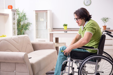 Young male invalid in wheelchair suffering at home