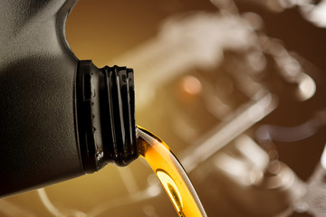Pouring oil lubricant motor car from black bottle on engine background change lube maintenance