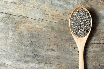 Chia seeds ( Salvia Hispanica ) in wooden spoon on wooden rustic background. Cereal healthy food...