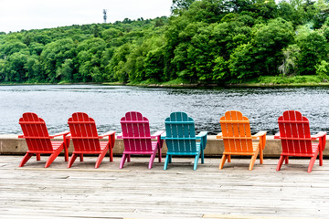 Colorful Wood Adirondack Chairs Lined Up on a Dock Overlooking a River