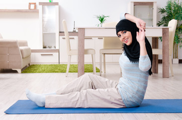 Young woman in hijab doing exercises at home