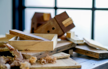 Close up shot of light brown wood frame is put on the table with wood pile and the other products that made from wood in the room with soft light.