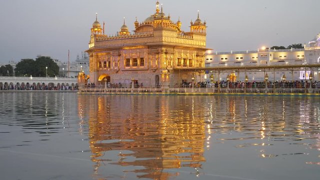 sunset shot of the beautiful golden temple and its reflection in amritsar, india
