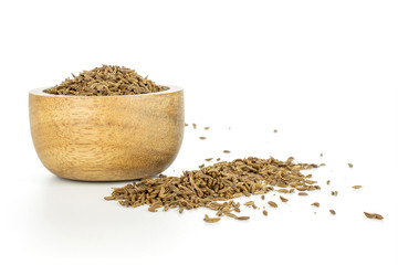 Lot of whole small dry caraway fruits in a wooden bowl isolated on white background