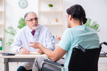 Obraz premium Male patient in wheel-chair visiting old doctor