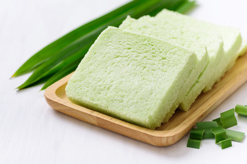 Sliced pandan bread on wooden plate and fresh pandan leaf 
