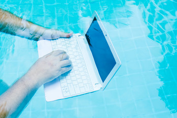 Male hands with a laptop working underwater. The concept of obstruction in the work. Blur Abstract...