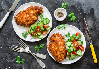 Tempura chicken chop with rice and fresh vegetable salad on a dark background, top view