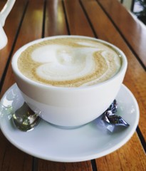cup of coffee with cream on wooden background