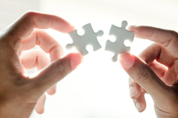Closeup hand of woman connecting jigsaw puzzle with sunlight effect, Business solutions, success and strategy concept