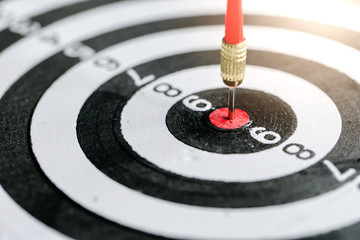 Dart arrow hitting in the target center of dartboard,business target