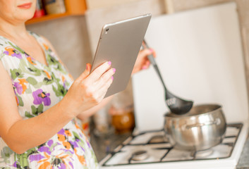Fototapeta na wymiar housewife woman holding a gadget smartphone or tablet to check receipt while cooking at the kitchen