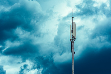 A tower with transmitters and mobile telephony antennas against the sky with clouds