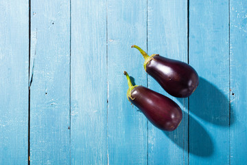two eggplants with shade on blue wood table