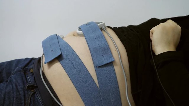 Detail of belts on  pregnant woman belly monitoring baby heart, fetal test non stress