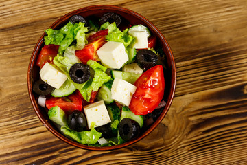 Greek salad with fresh vegetables, feta cheese and black olives on wooden table. Top view