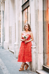 Portrait of a girl in a red dress and hat. Stylish bride on the streets of Rome.