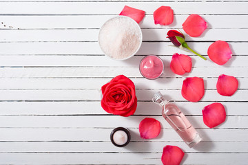 Fototapeta na wymiar perfume, body care and beauty products with red roses, pink petals on white wood table