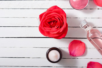 perfume, body care and beauty products with red roses, pink petals on white wood table