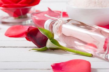 perfume, body care and beauty products with red roses, pink petals on white wood table