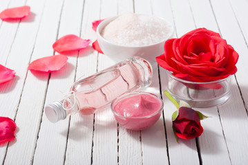 perfume, body care and beauty products with red roses, pink petals on white wood table