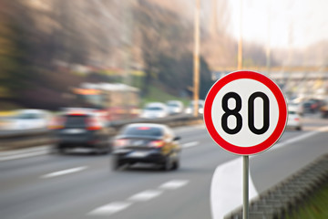 Traffic sign showing speed limit on a highway full of cars - obrazy, fototapety, plakaty