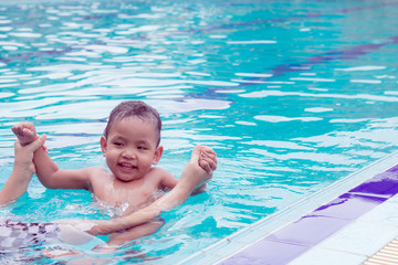 asian mother and baby in swimming pool.  little baby having fun in a swimming pool at thailand