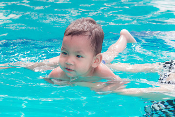 Fototapeta na wymiar asian mother and baby in swimming pool. little baby having fun in a swimming pool at thailand