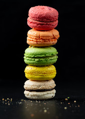 Colorful macarons on black background, french cake, nature light, copy space.