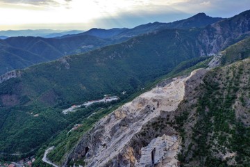 Obraz premium Aerial view of mountain of stone and marble quarries in the regional natural park of the Apuan Alps located in the Apennines in Tuscany, Massa Carrara Italy. Open pit mine