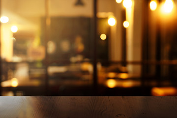 top of brown wood table with blur orange light at bar or pub in the dark night background