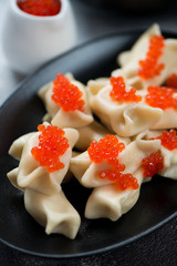 Close-up of vareniki or dumplings with cottage cheese and red caviar, selective focus