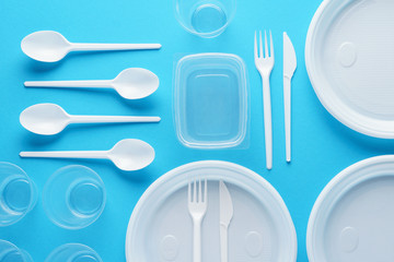 Various white plastic disposable tableware on blue background.