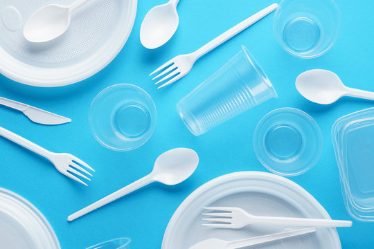 Various white plastic disposable tableware on blue background.