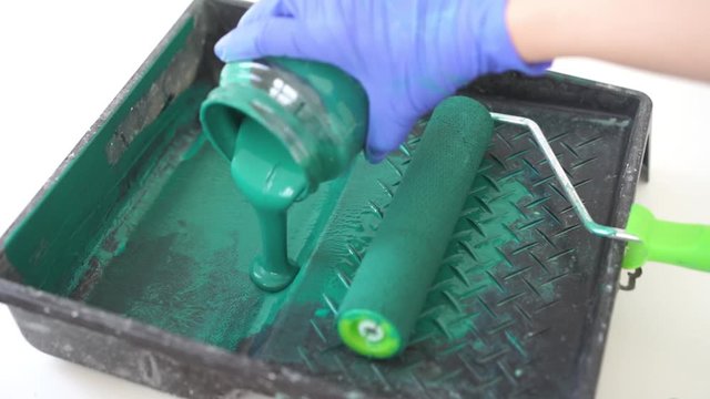 beauty slow motion. repair of the apartment - rolling green paint roller paint container closeup