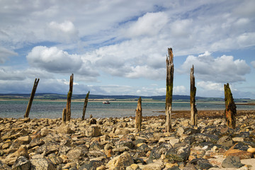 Beach and sea with remains of an old wooden pier in the foreground