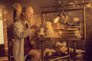 schoolgirl in white coat with owl on the shoulder making experiment in lab